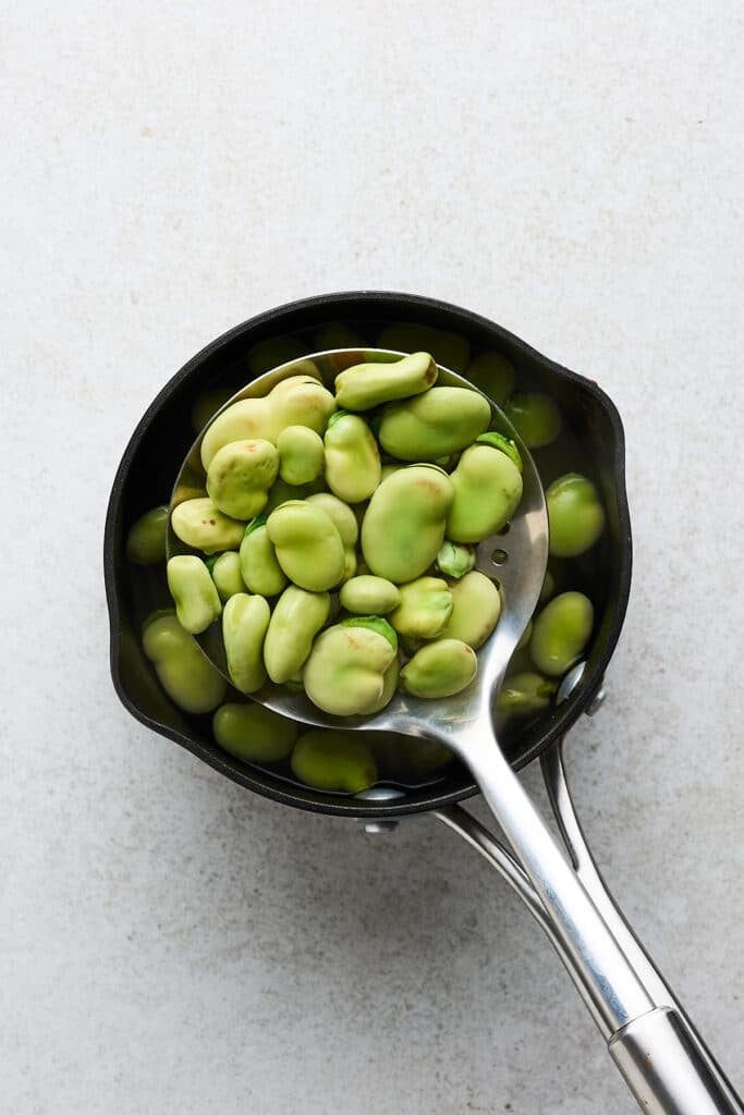 Spoon scooping fava beans up.