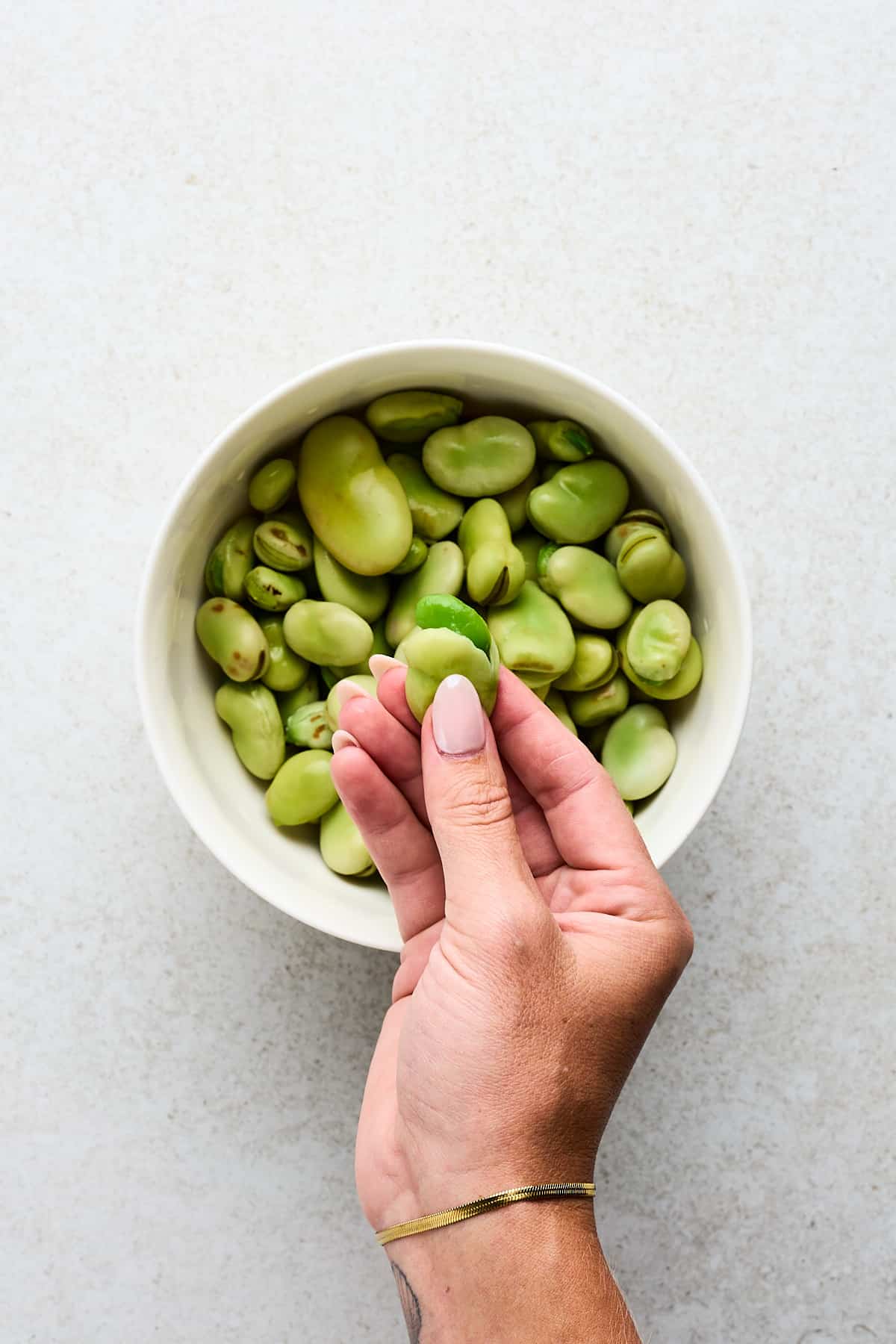 Peeling blanched fava beans.