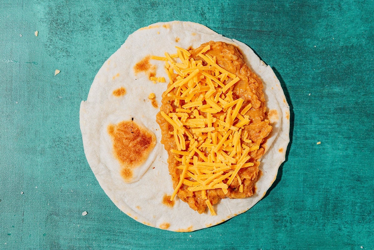 Tortilla with beans and cheese on a blue background.