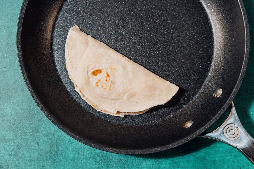 Cooking a bean and cheese taco in a saute pan.