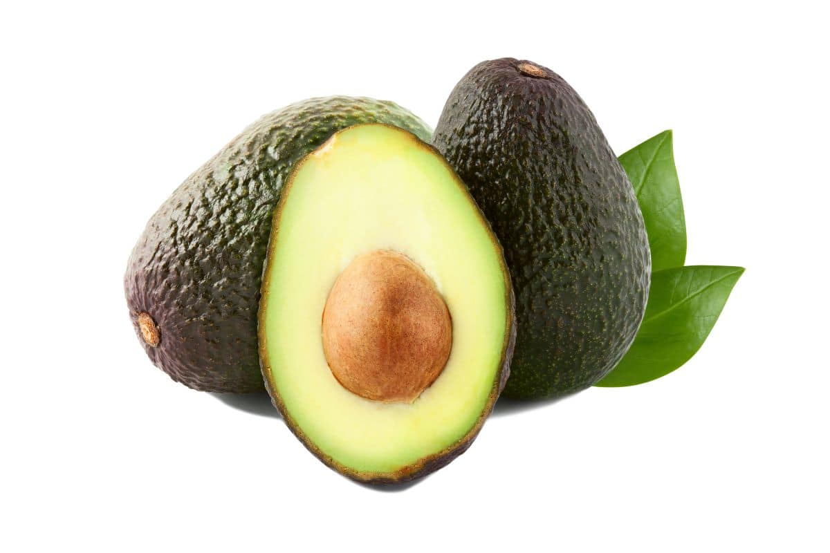 Lamb hass avocados cut open to show the seed on a white background.
