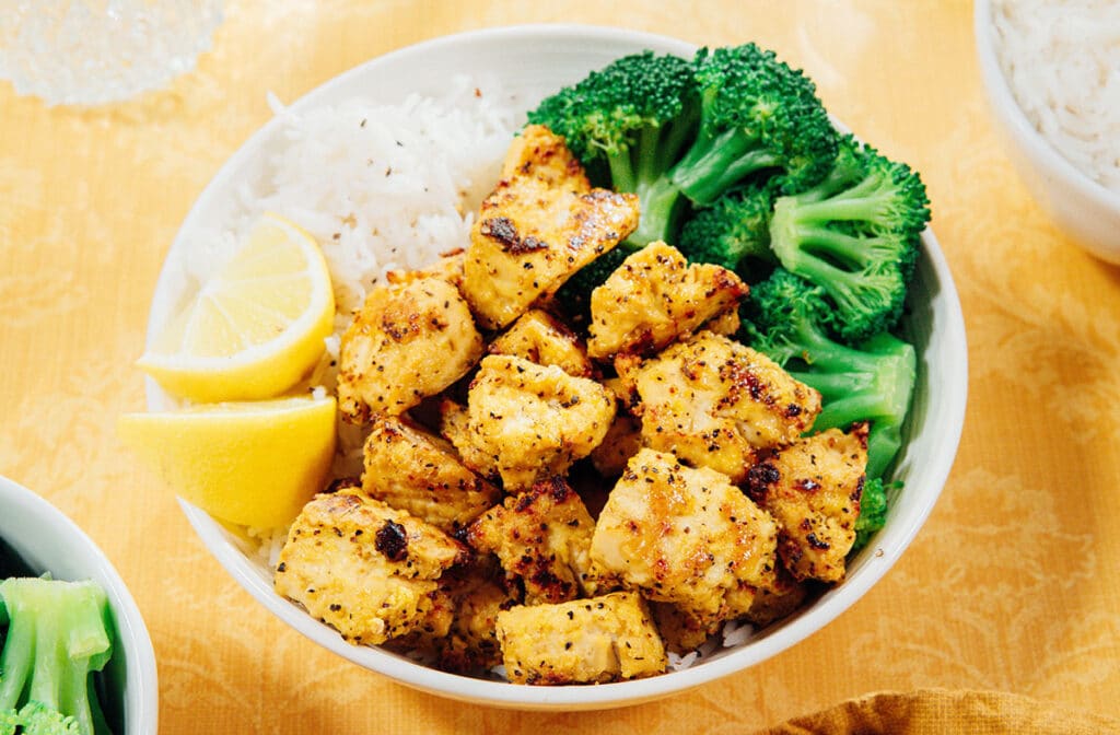 Lemon pepper tofu in a bowl with rice and broccoli.