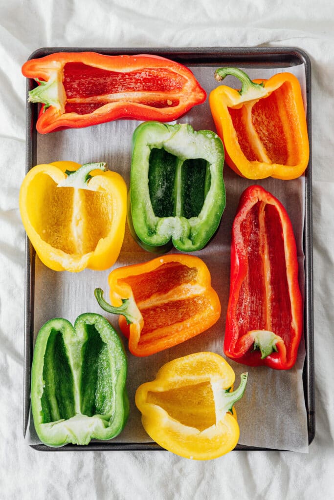 Halved bell peppers on a baking sheet.
