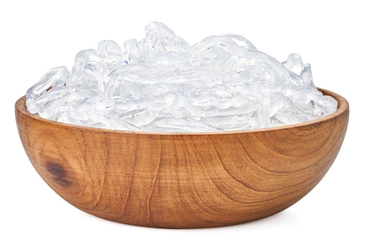 Shirataki noodles in a wood bowl on a white background.