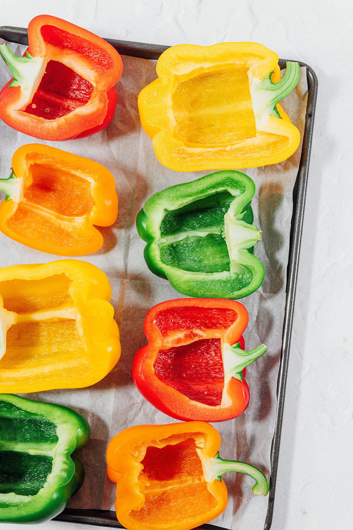 Multi colored peppers on a baking sheet.