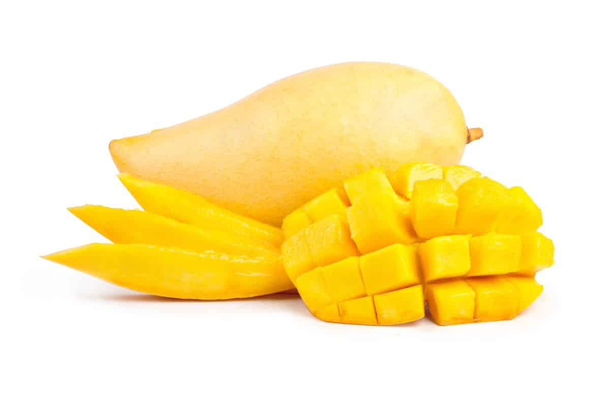 Honey mangoes with some sliced open on a white background.