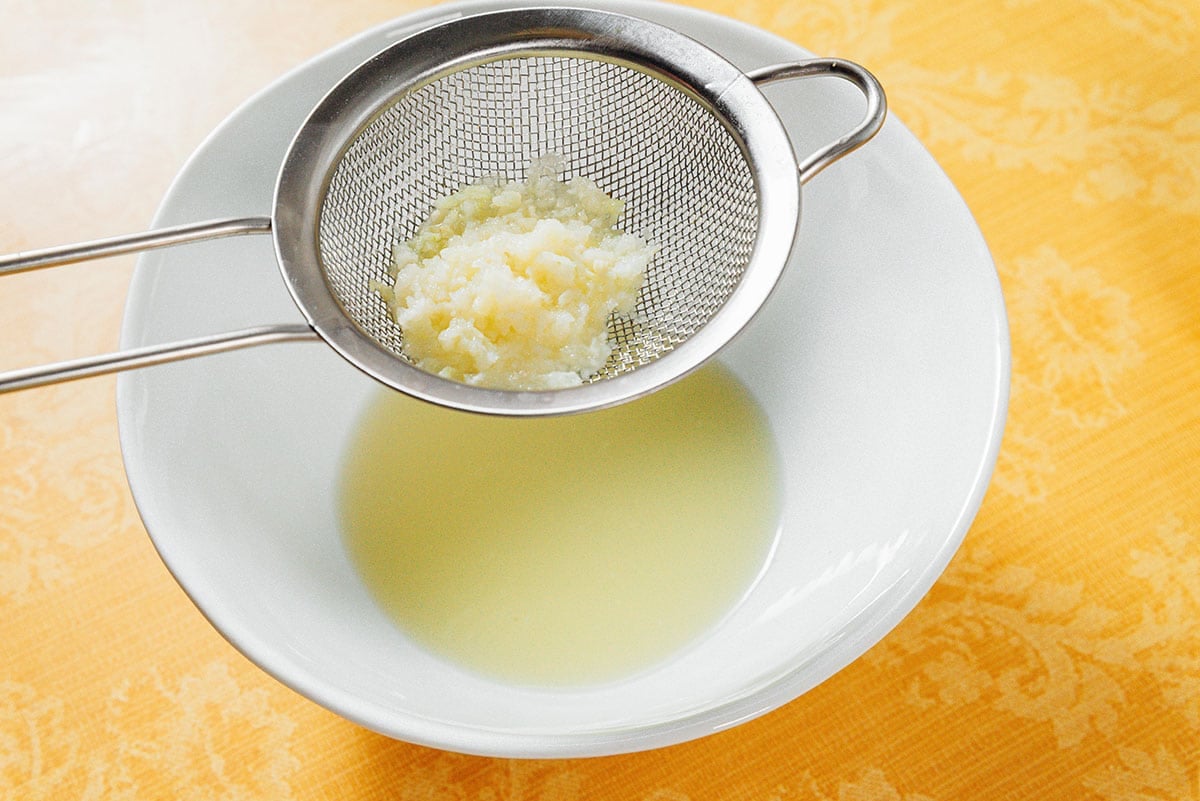 Garlic in a sieve over lemon juice.