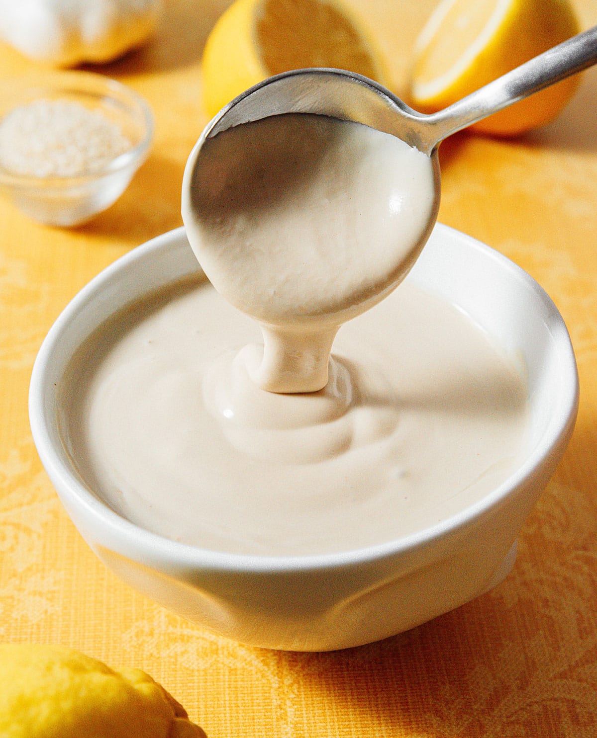 Lemon tahini dressing being stirred with a spoon in a bowl.