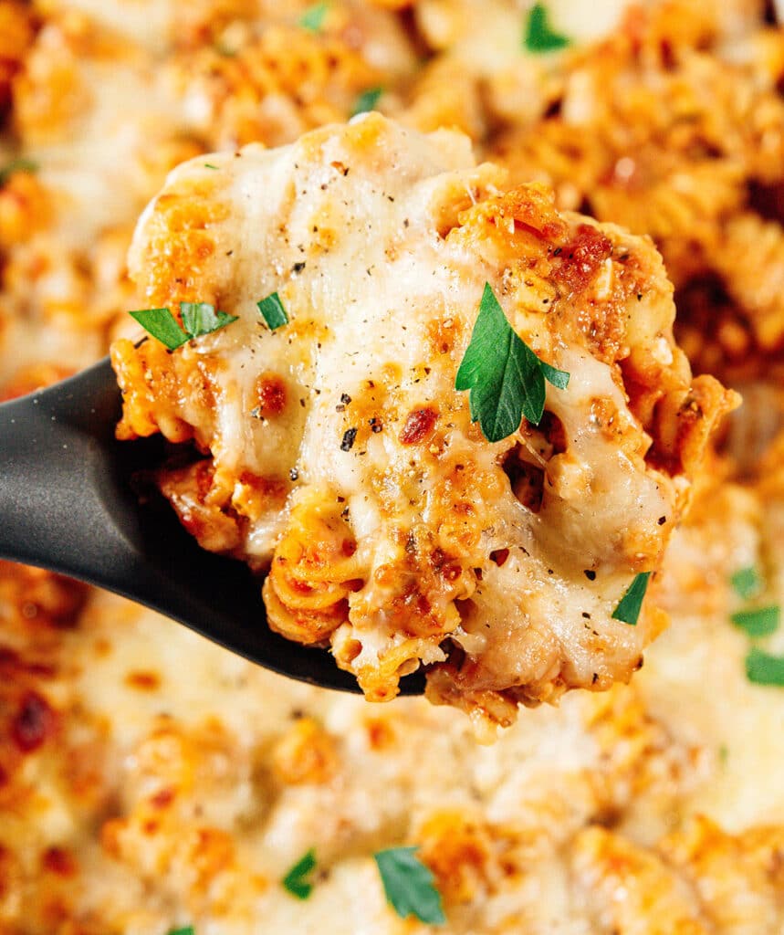 Rotini pasta bake in a on a serving spoon.