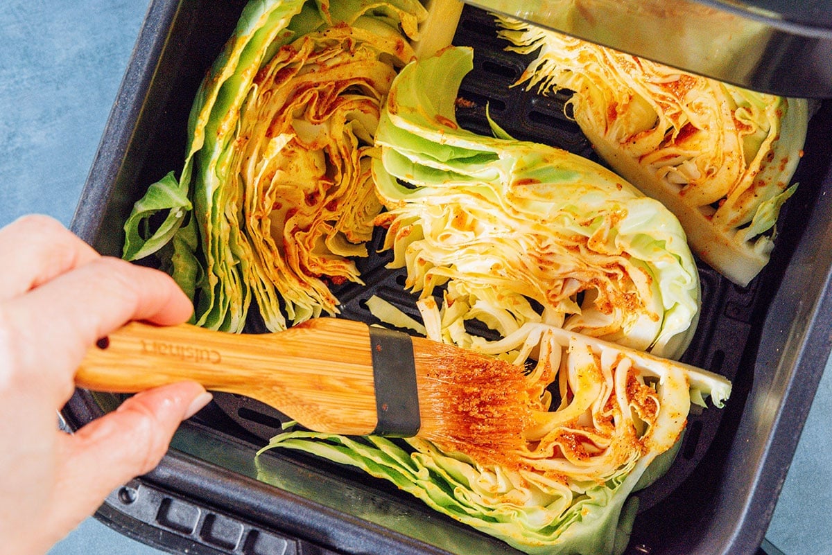 Brushing marinade on cabbage in an air fryer.
