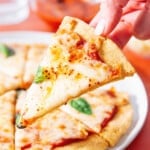 Chickpea pizza crust slice being held to show structure.