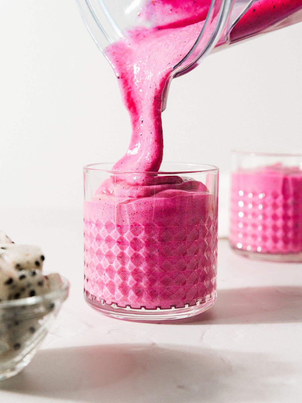 Pouring dragon fruit smoothie into a cup.