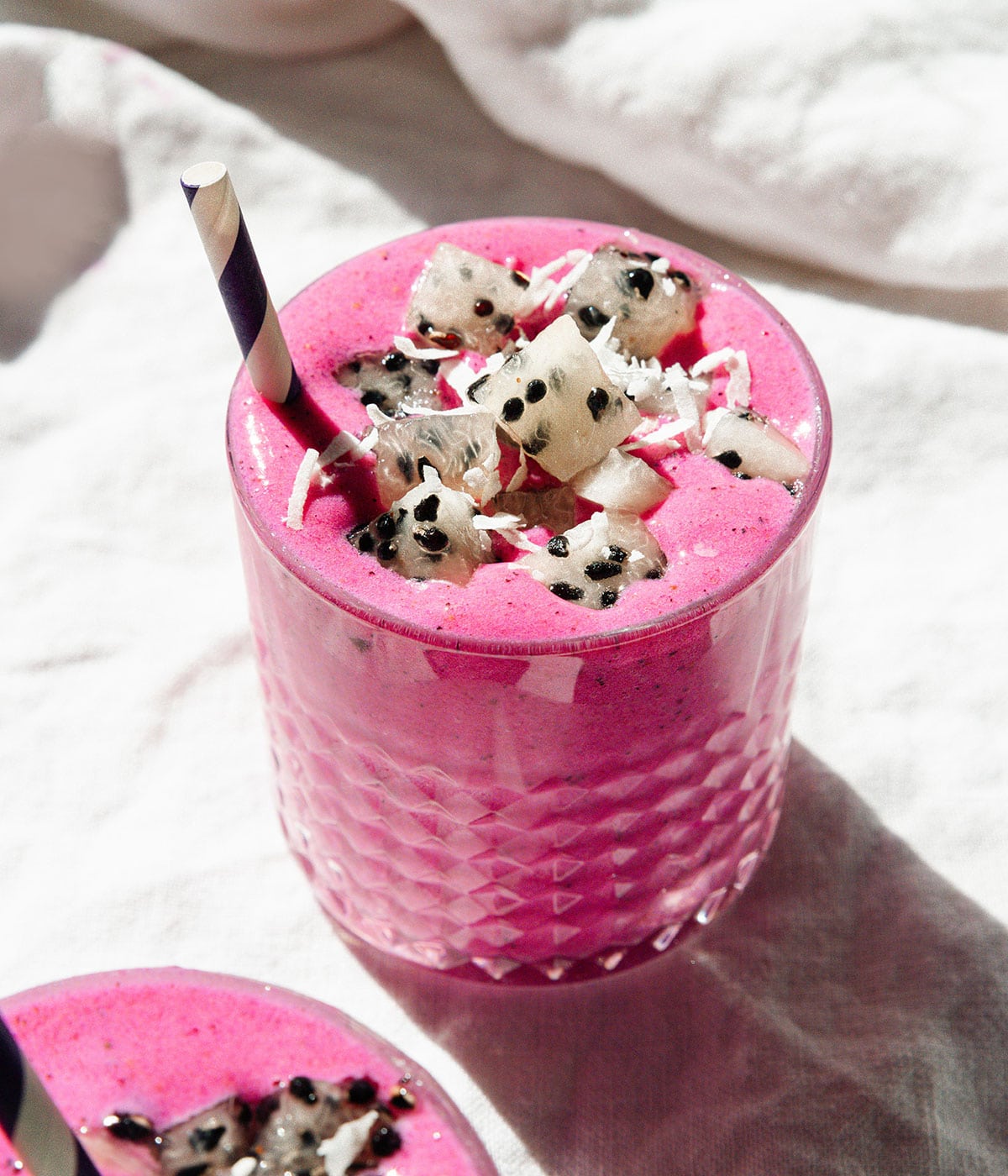 Pink dragon fruit smoothie with black and white dragon fruit cubes on top.