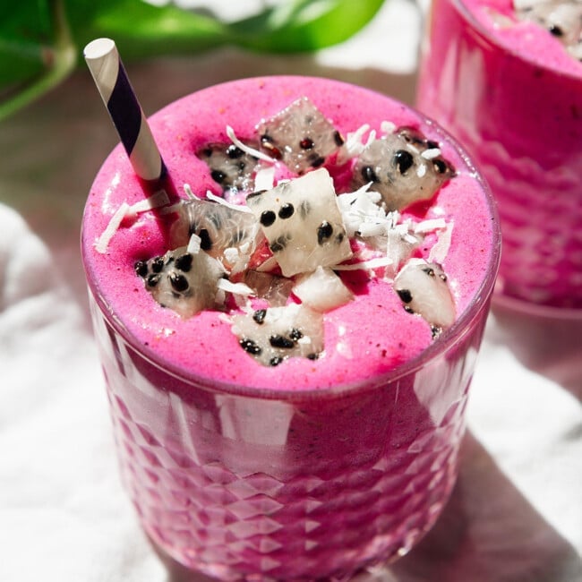 Pink dragon fruit smoothie with black and white dragon fruit cubes on top.
