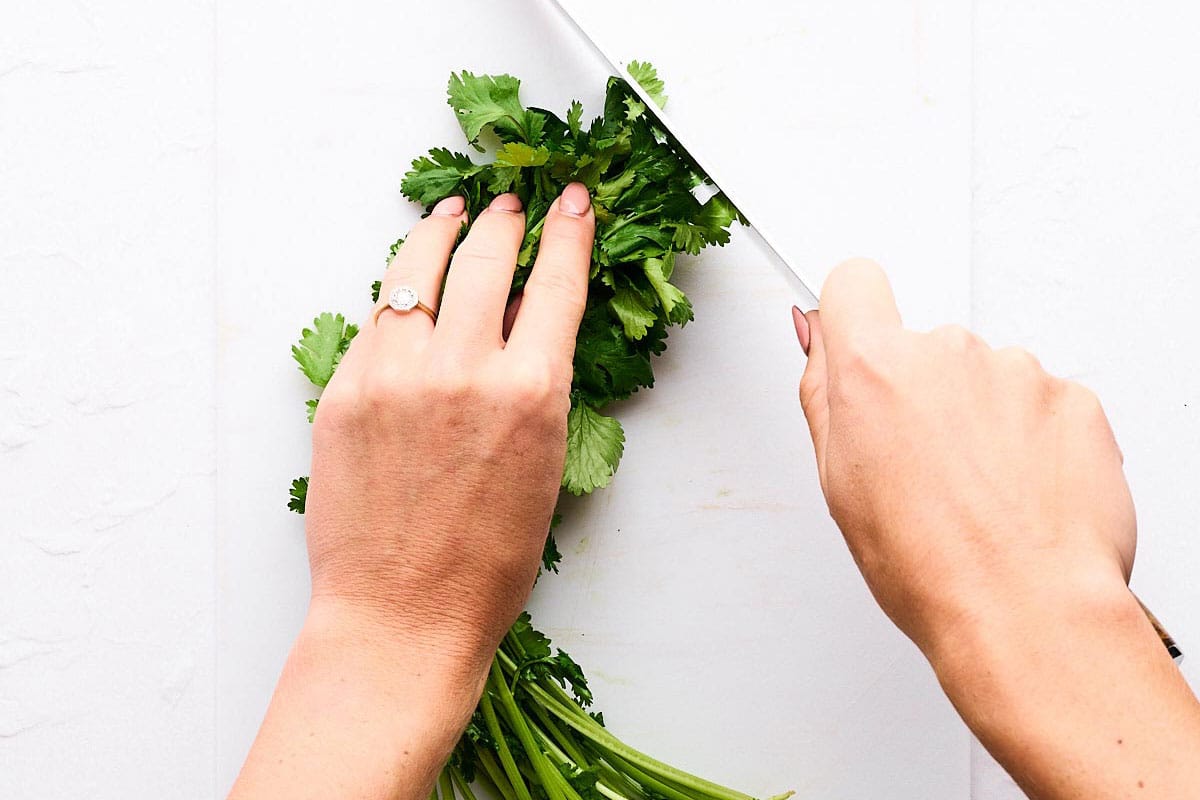 Cutting cilantro on a chopping board.