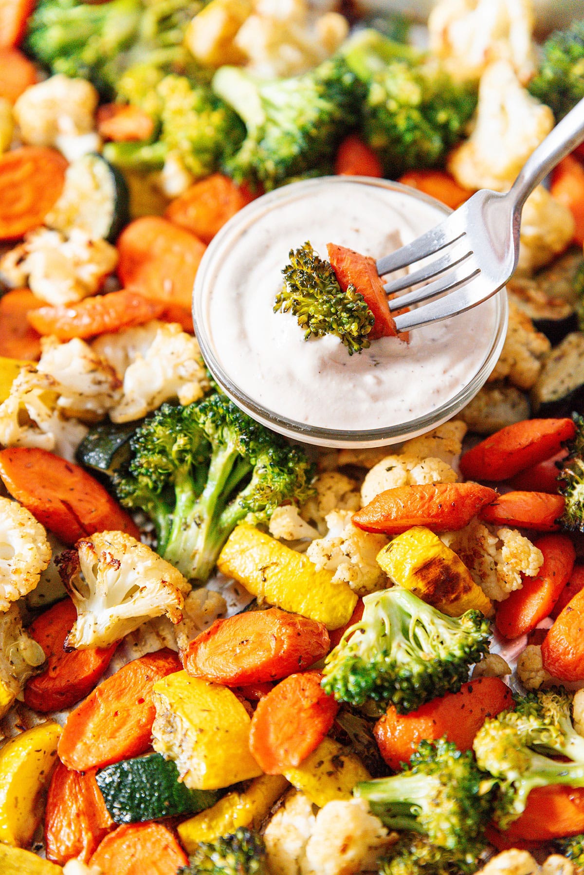 Roasted vegetable medley on a baking sheet with dip.