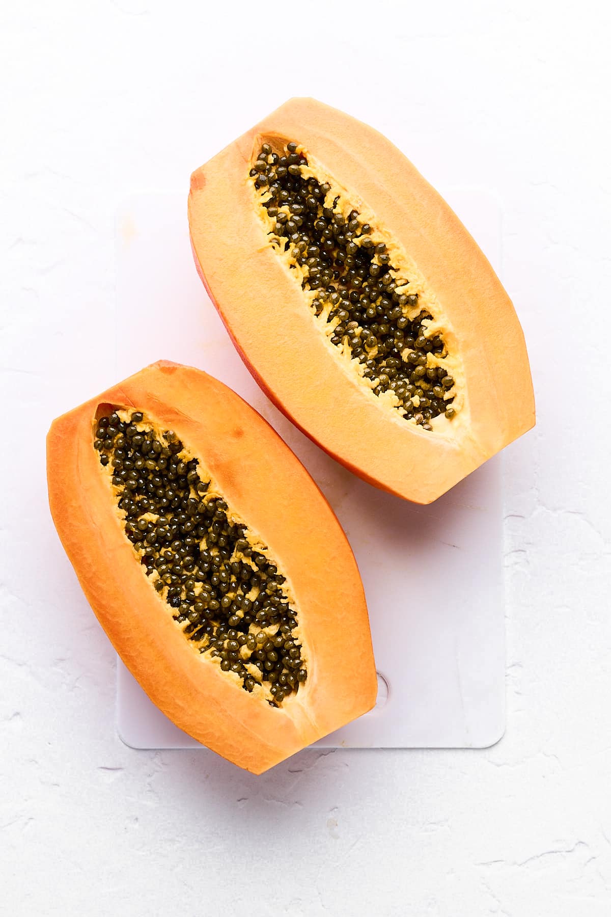 A papaya cut in half with seeds.