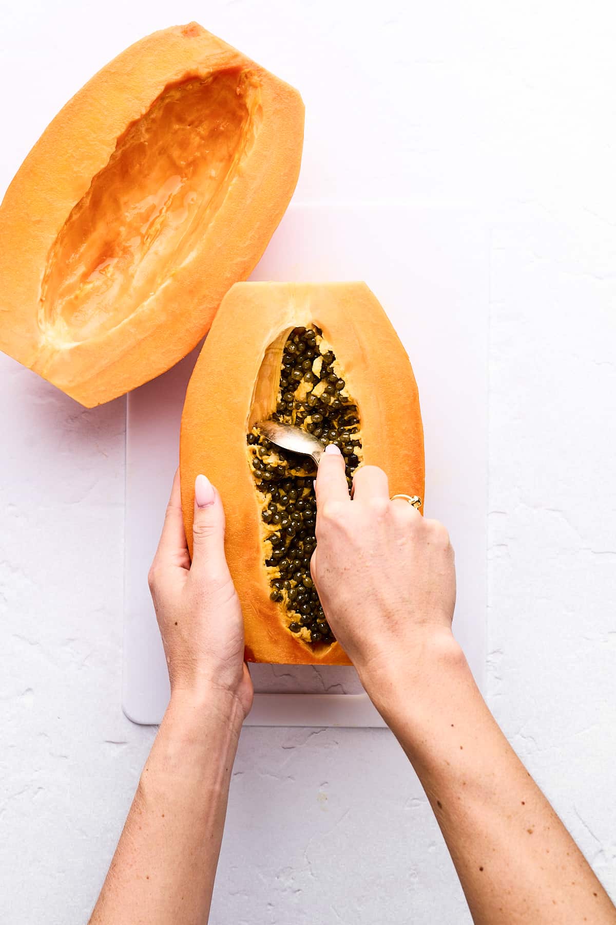 Scooping seeds out of a papaya half.