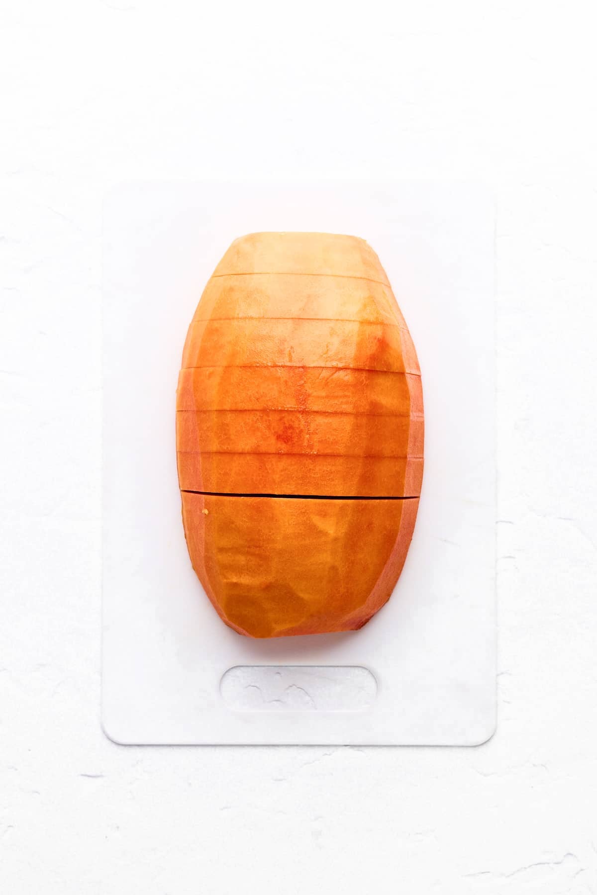 A papaya half cut into thick slices.