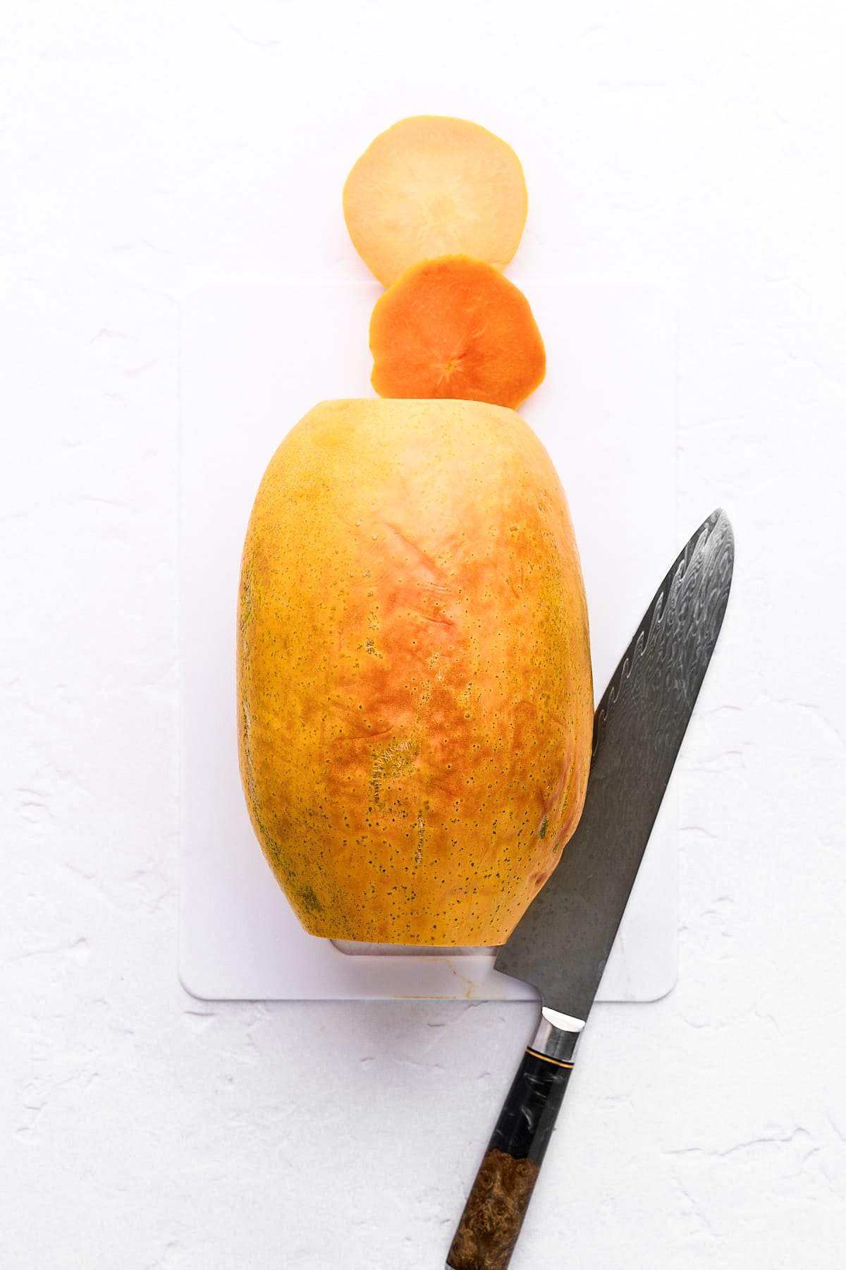 Ends trimmed off a whole papaya.
