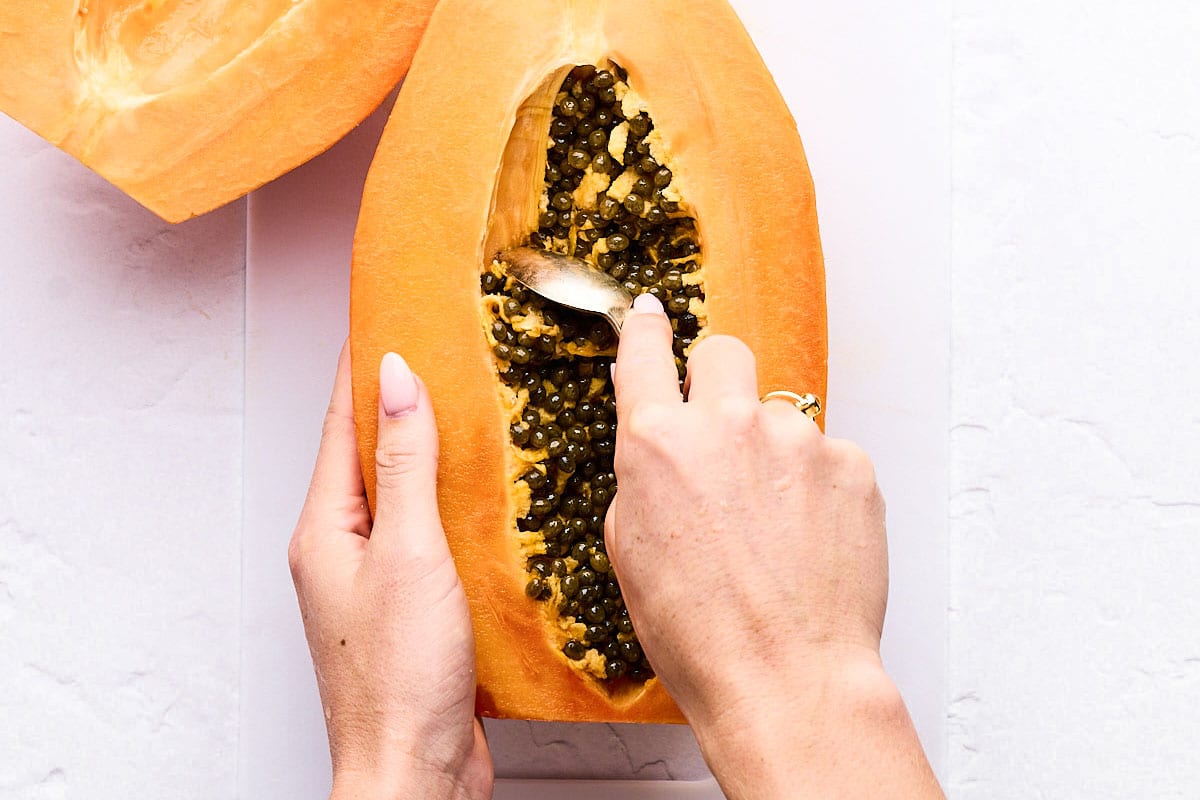 Scooping seeds out of papaya.