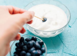 Dipping a blueberry in yogurt with toothpick