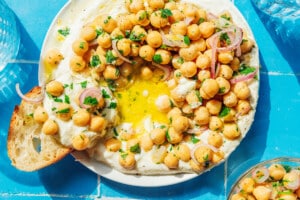 Scooping marinated chickpeas with whipped feta on a piece of bread.