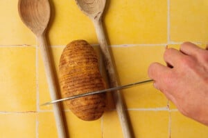 How to cut hasselback potatoes with spoons on either side of the potato.