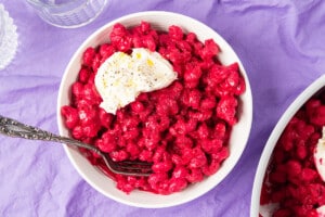 Beet pink pasta with burrata cheese in a bowl.