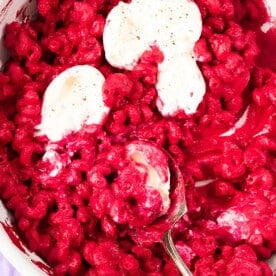 Beet pink pasta with burrata cheese in a pan.