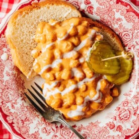 Nashville hot chickpeas in a red bowl with bread and a pickle.