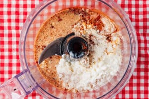 Adding ingredients for high protein Nashville hot sauce to a food processor.