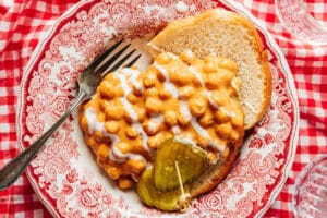 Nashville hot chickpeas in a red bowl with bread and a pickle.