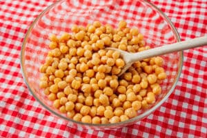 Stirring chickpeas with oil in a bowl.