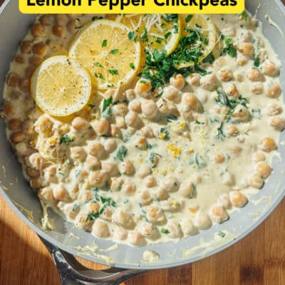 A skillet of creamy lemon pepper chickpeas garnished with lemon slices and fresh herbs, held over a wooden surface. Text reads: High Protein Lemon Pepper Chickpeas.