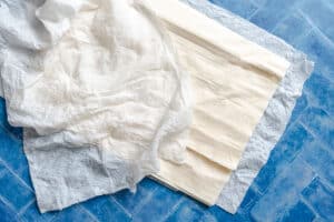 Sheets of phyllo dough and a crumpled piece are laid out on a blue tile surface.