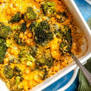 A comforting Chickpea Ranch Casserole, this dump and bake dish features broccoli, chickpeas, rice, and melted cheddar cheese, all baked together and served with a spoon in one corner.