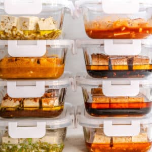Stacked clear containers filled with different marinated tofu cubes, each showing various colored sauces and seasonings.