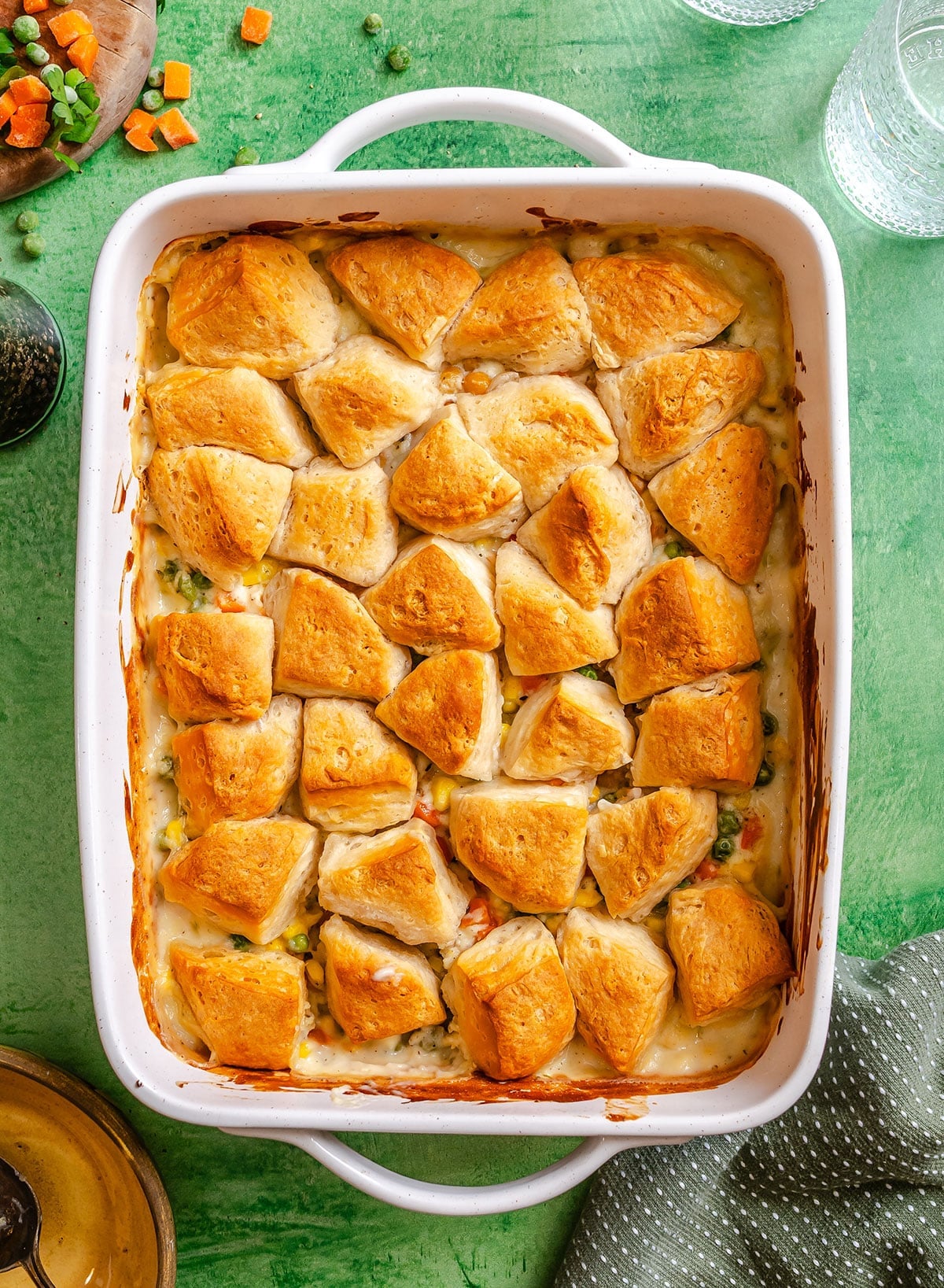 A white baking dish filled with a Vegetable Pot Pie casserole, topped with golden-brown biscuit pieces and a creamy filling with visible vegetables—an easy dump and bake meal.