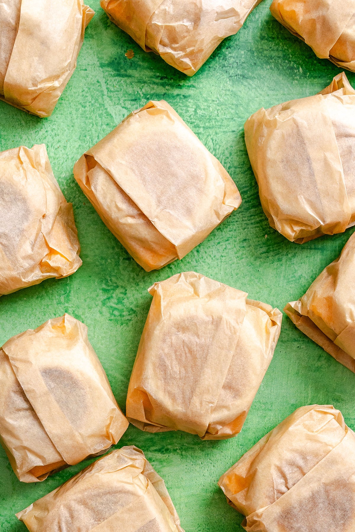Several rectangular parcels wrapped in brown parchment paper are arranged on a bright green surface.