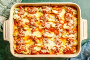 A rectangular baking dish filled with baked stuffed shells covered in tomato sauce and melted cheese.