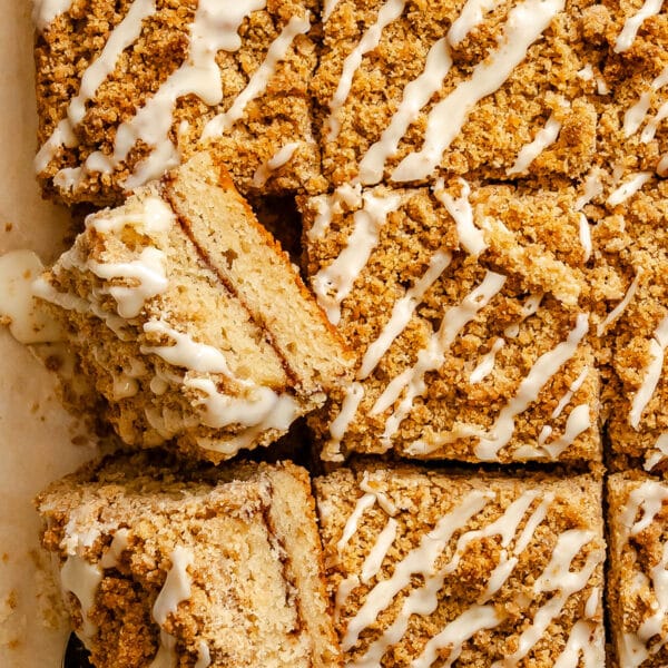 Close-up of sliced crumb cake squares with a crumbly topping and white icing drizzled on top.
