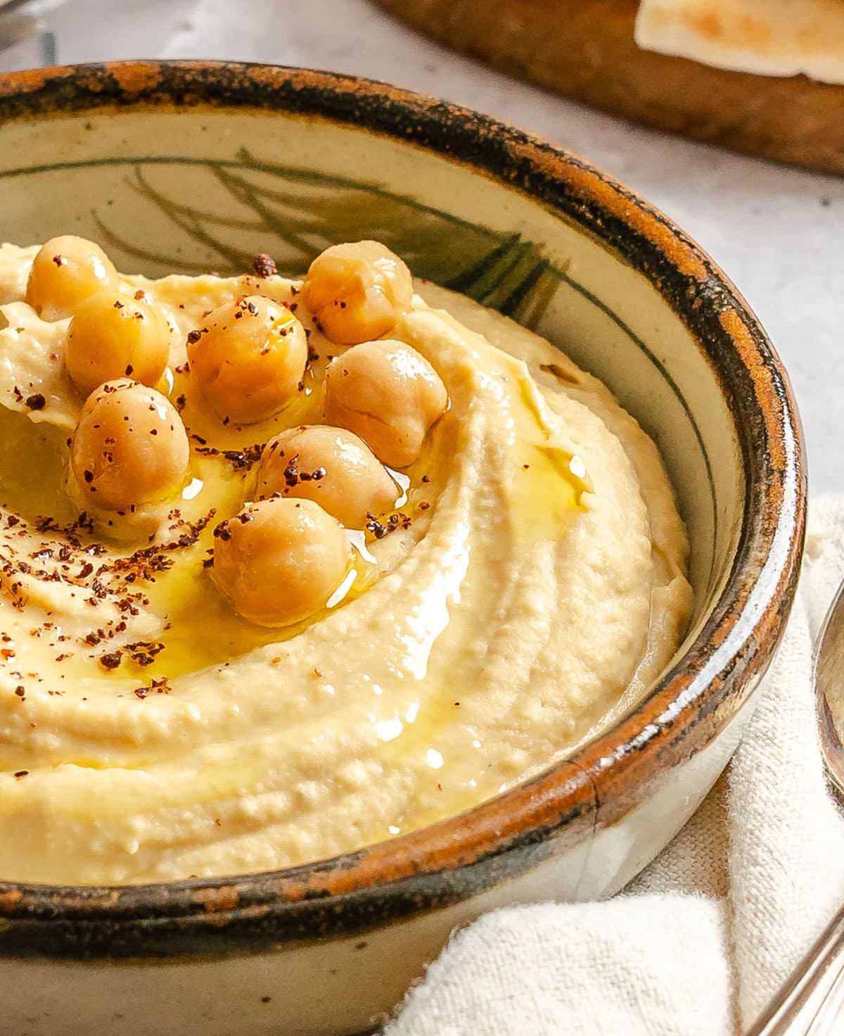 A bowl of hummus topped with whole chickpeas, a drizzle of olive oil, and sprinkled spices.