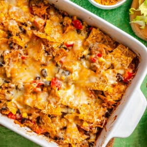 A rectangular casserole dish filled with a baked Vegetarian Taco Casserole featuring black beans, corn, red peppers, tortilla chips, and melted cheese for an easy dump and bake meal.