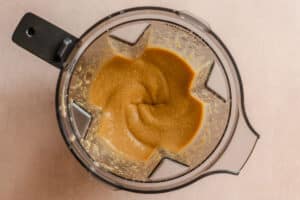 Blender filled with a smooth, light brown mixture viewed from above on a neutral background.