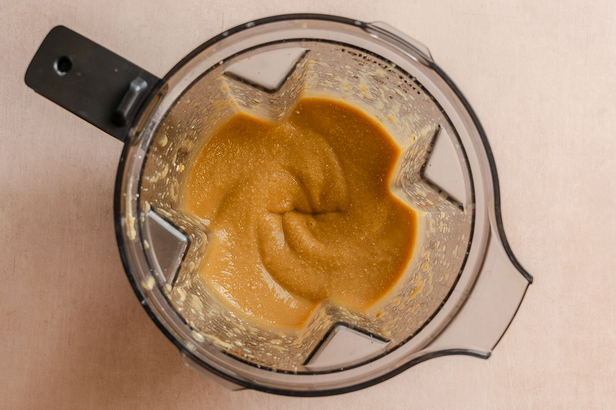 Blender filled with a smooth, light brown mixture viewed from above on a neutral background.