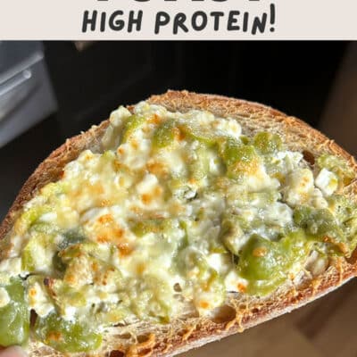 A hand holds a slice of martini toast topped with melted cheese and green peppers. The text above reads, “Martini Toast High Protein!”.