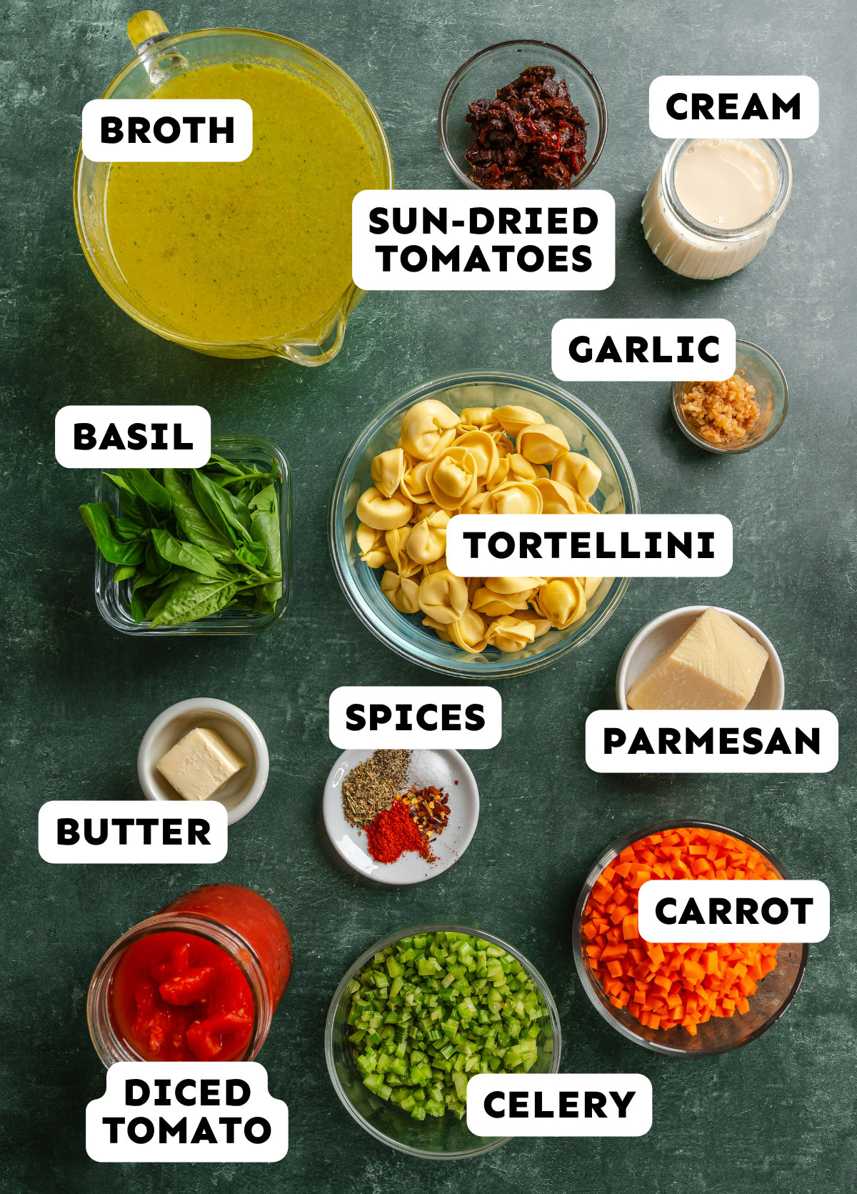 Ingredients for this cozy Tortellini Soup, inspired by the popular Marry Me Soup, are arranged on a countertop, including broth, cream, sun-dried tomatoes, spices, vegetables, tortellini, parmesan, basil, butter, garlic, and diced tomatoes.