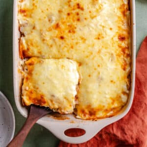 A baking dish filled with cheesy lasagna casserole, with one square piece being lifted out using a wooden spatula, makes for a comforting casserole recipe perfect for any meal.