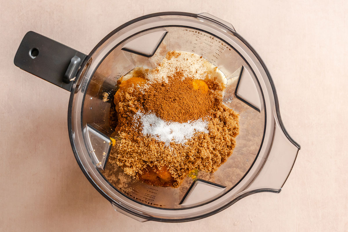 Overhead view of a blender containing brown sugar, cinnamon, salt, and other ingredients, ready to be mixed.